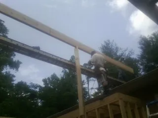 Carpenter setting a ridge beam over a new addition frame — Ice Dam Removal by Roofing Brothers in Hydes