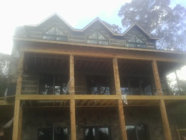 Dormers and porch framing on a large log home under construction — Roof Coating work by our crew in Hydes