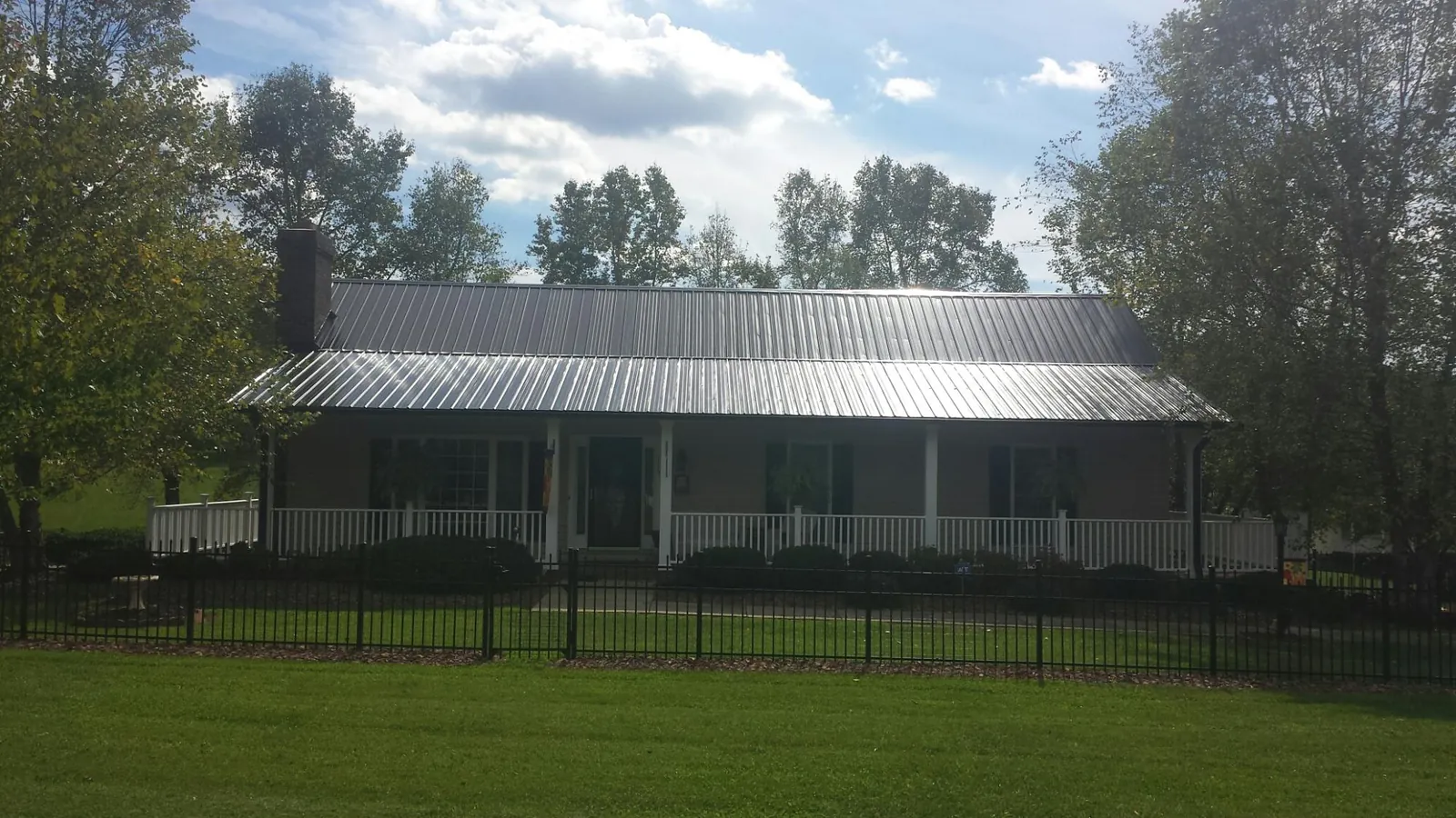 Gray metal roof on a brick ranch with a full width front porch — Gutter Guard Installation work by our crew in Hydes