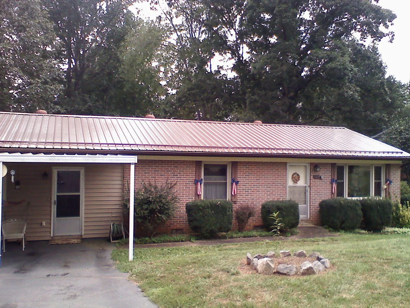 Bronze metal roof and carport on a brick ranch home — Roof Repair work by our crew in Hydes