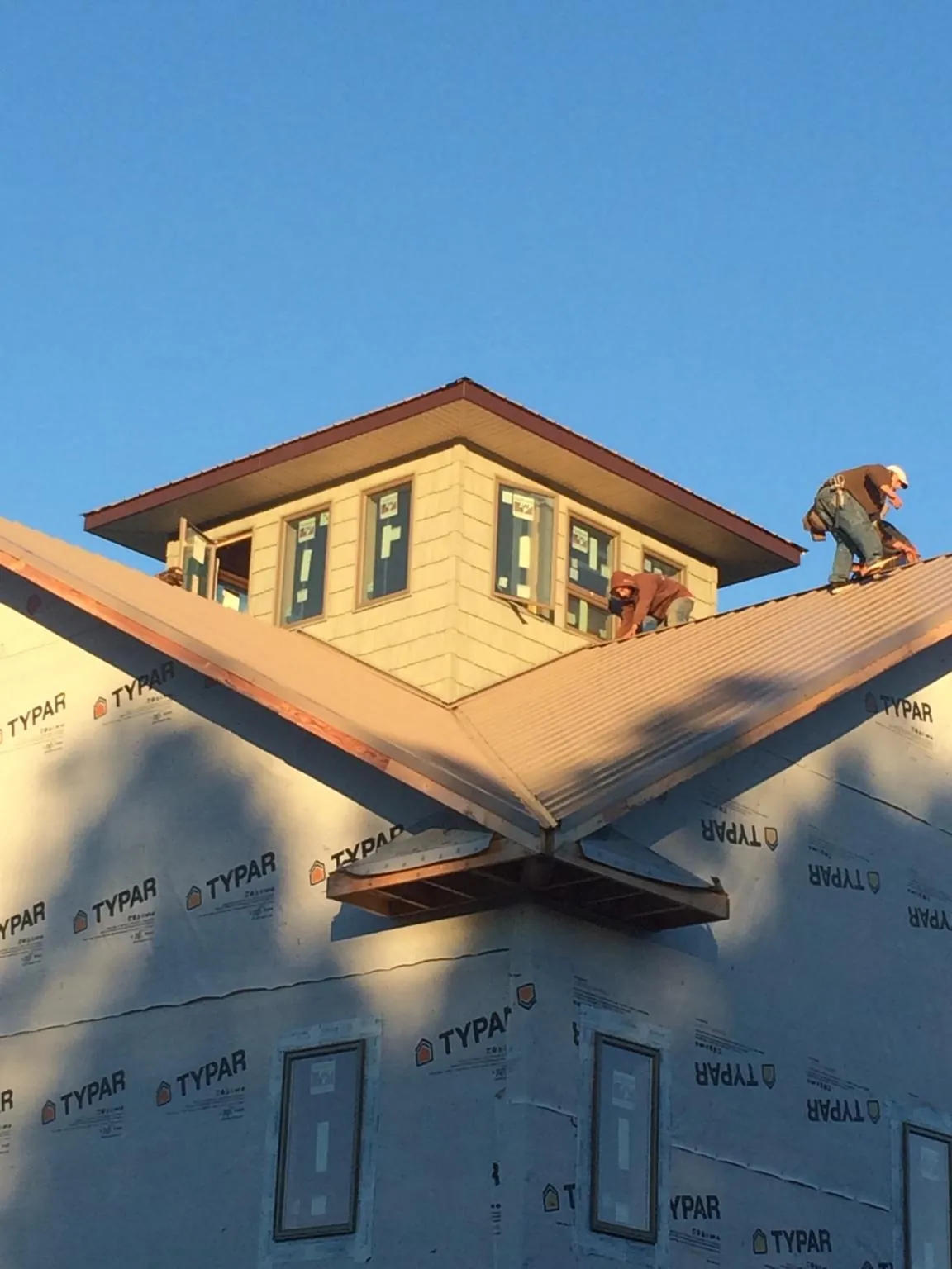 Roofers working around a rooftop cupola on a new metal roof at sunset — Roof Waterproofing in Hydes by Roofing Brothers